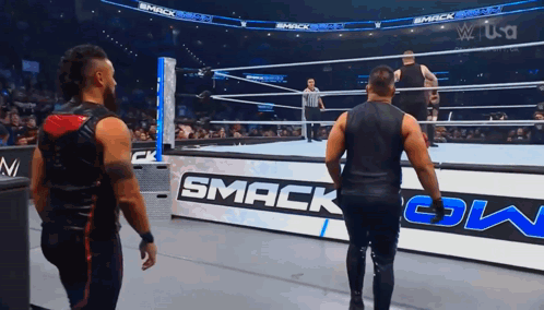 Two Men Are Standing In A Wrestling Ring With A Sign That Says Smack Down GIF