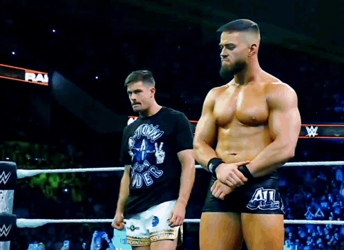 two men are standing in a wrestling ring with one wearing a shirt that says " storm rider " on it