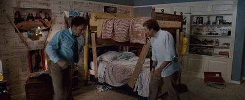 Two Men Are Standing In Front Of A Bunk Bed In A Room GIF