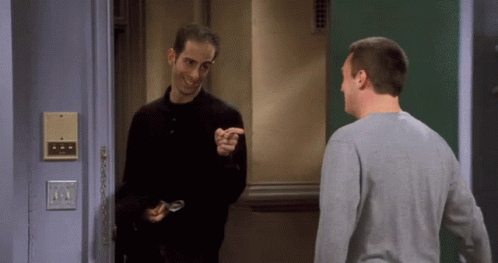 Two Men Are Standing In Front Of A Door And One Is Pointing GIF