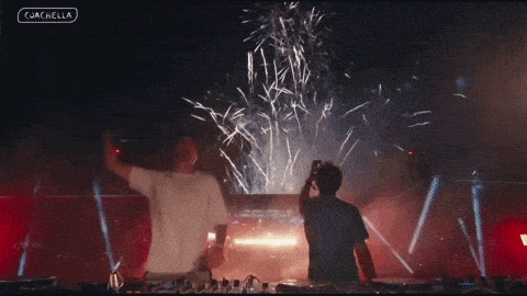 Two Men Are Standing In Front Of A Fireworks Display And The Words Coachella Are On The Bottom Left GIF