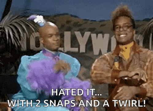 Two Men Are Standing In Front Of A Hollywood Sign GIF