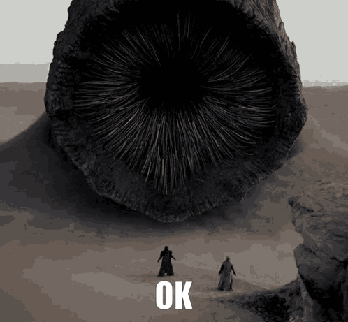 Two Men Are Standing In Front Of A Large Object That Says Ok On The Bottom GIF