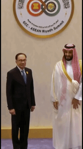 Two Men Are Standing In Front Of A Logo That Says Gcc Asean Riyadh Summit GIF