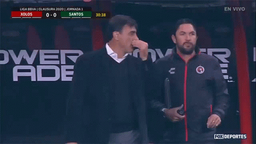 Two Men Are Standing In Front Of A Powerade Ad GIF