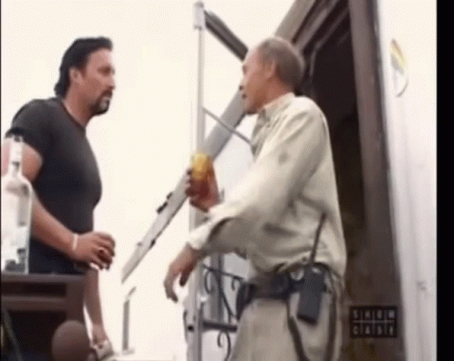 Two Men Are Standing In Front Of A Sign That Says ' Shield ' On It GIF