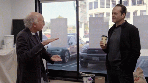 Two Men Are Standing In Front Of A Window With A Sign That Says ' A Few Dollars More ' On It GIF