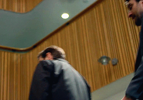 Two Men Standing In Front Of Wood Paneling GIF