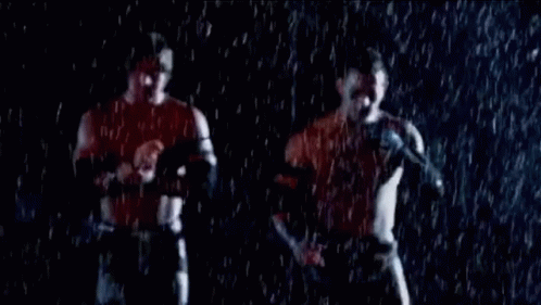 Two Men Are Standing In The Rain Holding Hands And Talking Into Microphones . GIF