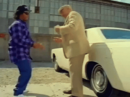 two men are standing next to a white car .