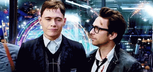 Two Men Are Standing Next To Each Other And Looking At Each Other . One Of The Men Is Wearing Glasses . GIF
