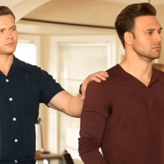 two men are standing next to each other and one has his hand on the shoulder of the other .