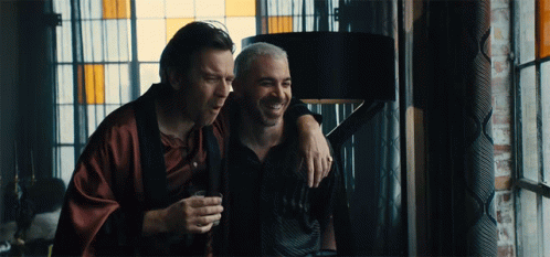 Two Men Are Standing Next To Each Other And One Is Holding A Glass GIF