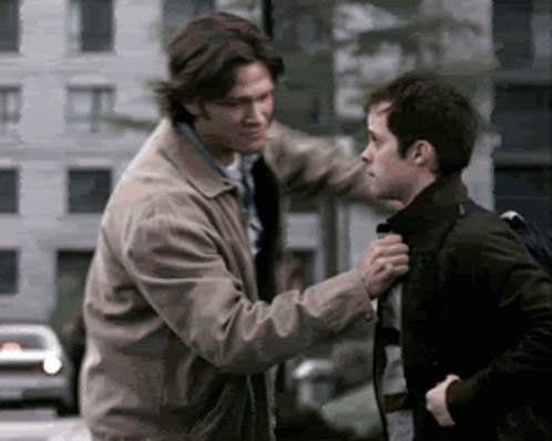 Two Men Are Standing Next To Each Other And One Is Holding The Other 'S Collar GIF