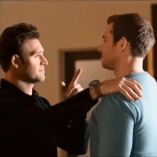 two men are standing next to each other and one man is pointing at the other .