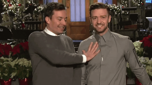 Two Men Are Standing Next To Each Other And One Of Them Is Touching The Chest Of The Other GIF