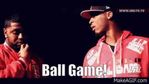 two men are standing next to each other and one of them is wearing a red jacket that says ball game on it .