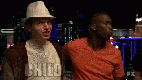 Two Men Are Standing Next To Each Other And One Of Them Is Wearing An Orange Shirt With The Word Fx On It GIF