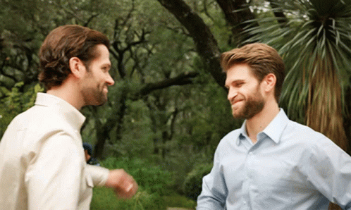 Two Men Are Standing Next To Each Other And Talking GIF