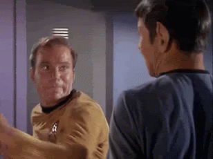 Two Men Are Standing Next To Each Other And Talking In A Room . GIF