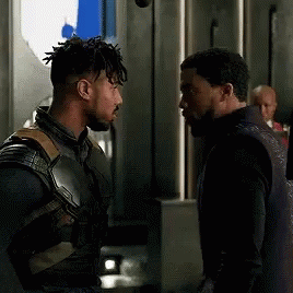 Two Men Are Standing Next To Each Other And Talking To Each Other In A Dark Room . GIF