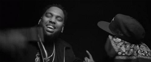 Two Men Are Standing Next To Each Other In A Black And White Photo . One Of The Men Is Wearing A Bandana . GIF