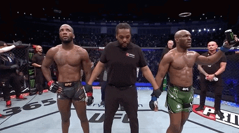 Two Men Are Standing Next To Each Other In A Boxing Ring And One Of Them Is Wearing A Ufc Shorts GIF