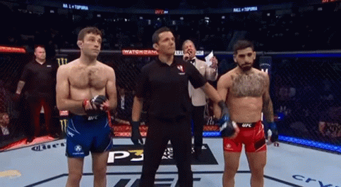 Two Men Are Standing Next To Each Other In A Boxing Ring With A Referee . GIF