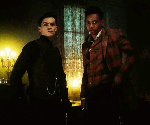 Two Men Are Standing Next To Each Other In A Dark Room And One Is Smoking A Cigarette GIF