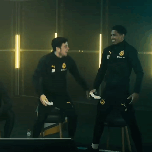 Two Men Are Standing Next To Each Other In A Dark Room And One Of Them Is Holding A Remote Control GIF