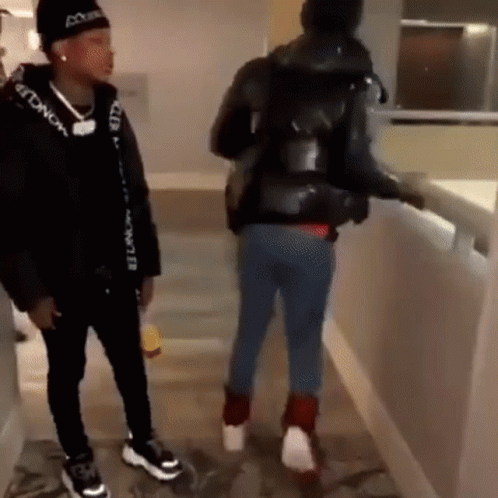 Two Men Are Standing Next To Each Other In A Hallway . One Of The Men Is Wearing A Black Moncler Jacket . GIF