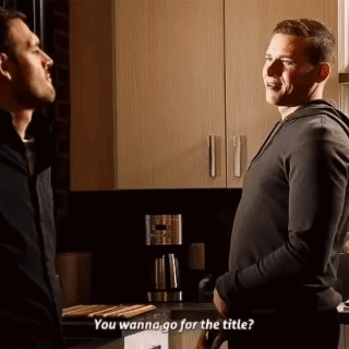 two men are standing next to each other in a kitchen and talking .