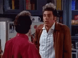 Two Men Are Standing Next To Each Other In A Kitchen Talking . GIF