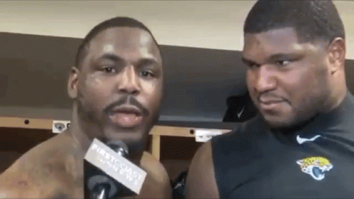 Two Men Are Standing Next To Each Other In A Locker Room Talking Into Microphones . GIF