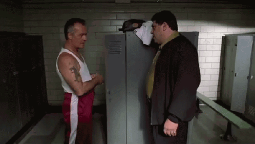 Two Men Are Standing Next To Each Other In A Locker Room Talking . GIF