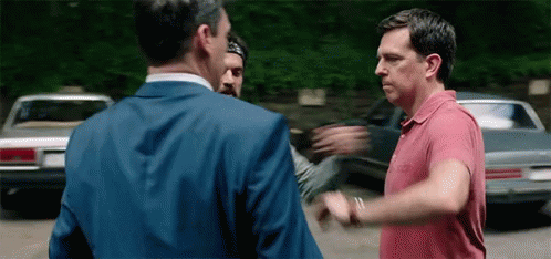 Two Men Are Standing Next To Each Other In A Parking Lot . GIF