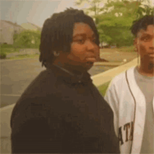 Two Men Are Standing Next To Each Other In A Parking Lot . GIF