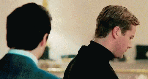 Two Men Are Standing Next To Each Other In A Room And Looking At Each Other . GIF