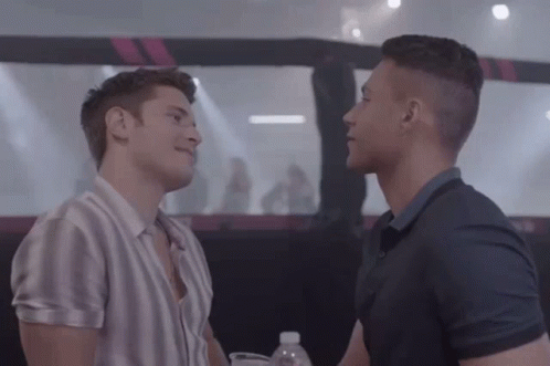 Two Men Are Standing Next To Each Other In A Room And Looking At Each Other . GIF