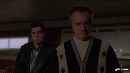 Two Men Are Standing Next To Each Other In A Room . One Of The Men Is Wearing A Sweater And A Leather Jacket . GIF