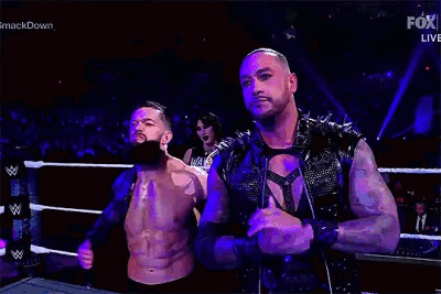 Two Men Are Standing Next To Each Other In A Wrestling Ring . One Of The Men Has A Beard . GIF