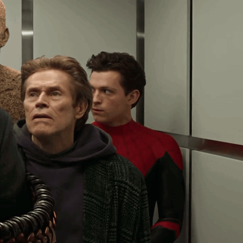 Two Men Are Standing Next To Each Other In An Elevator And One Of Them Is Wearing A Red Suit GIF