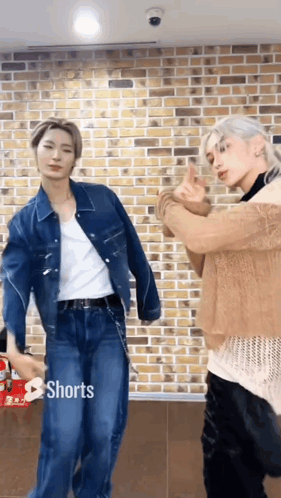 Two Men Are Standing Next To Each Other In Front Of A Brick Wall . GIF