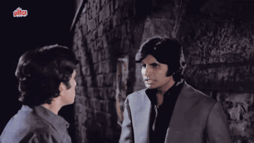 Two Men Are Standing Next To Each Other In Front Of A Brick Wall With A Sign That Says Ultra GIF