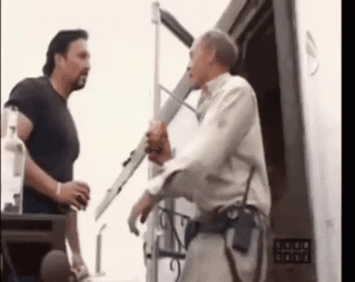 Two Men Are Standing Next To Each Other In Front Of A Building . GIF