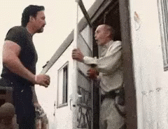Two Men Are Standing Next To Each Other In Front Of A Building . GIF