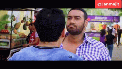 Two Men Are Standing Next To Each Other In Front Of A Fruit Stand And A Sign That Says Janmajit GIF