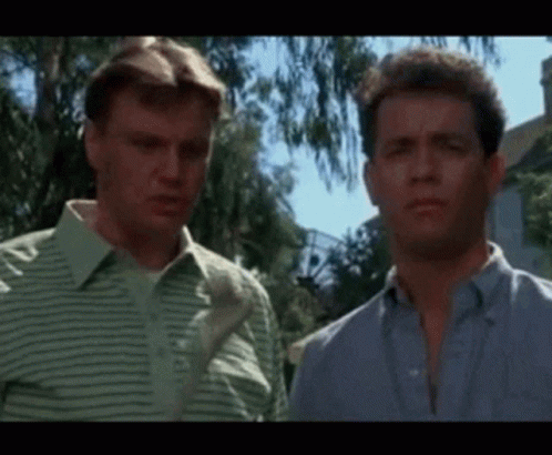 Two Men Are Standing Next To Each Other In Front Of A House And Looking At Each Other . GIF