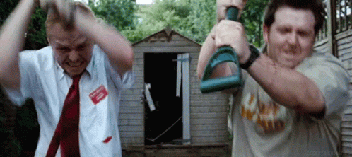 Two Men Are Standing Next To Each Other In Front Of A Shed Holding Dumbbells In Their Hands . GIF