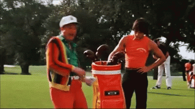 Two Men Are Standing Next To Each Other On A Golf Course . GIF